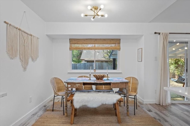 dining area featuring an inviting chandelier, baseboards, and wood finished floors