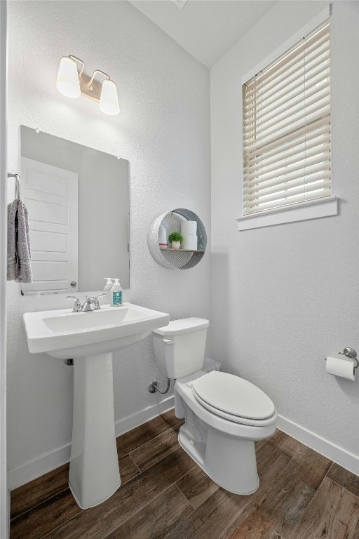 bathroom with toilet, baseboards, and wood finished floors