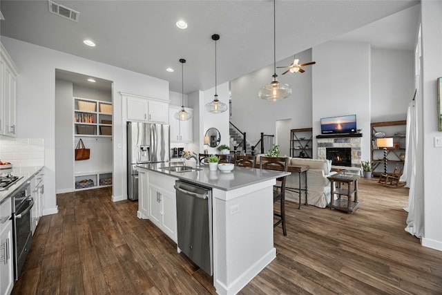 kitchen with appliances with stainless steel finishes, a kitchen island with sink, and white cabinetry