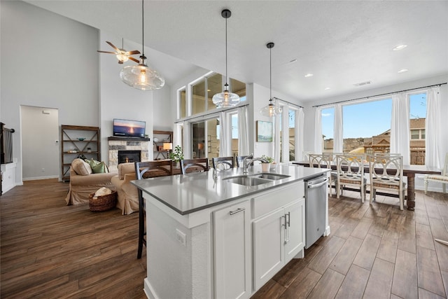 kitchen featuring a kitchen island with sink, a sink, white cabinetry, open floor plan, and hanging light fixtures