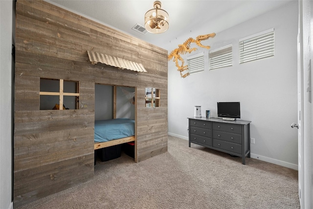 bedroom with baseboards, carpet floors, visible vents, and wooden walls