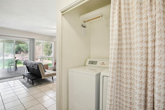 clothes washing area featuring light tile patterned floors, laundry area, washer and clothes dryer, and a textured ceiling