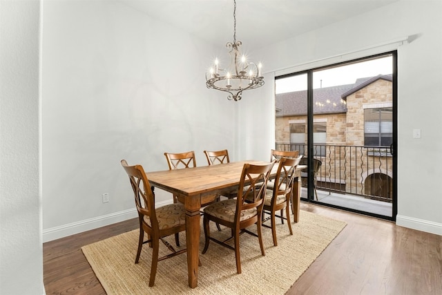 dining area featuring a chandelier, wood finished floors, and baseboards