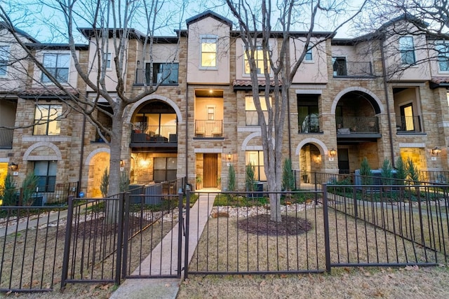 townhome / multi-family property featuring a fenced front yard and a gate