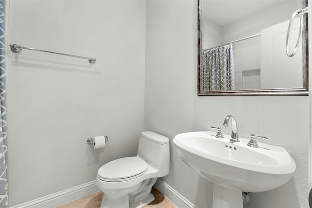 full bathroom featuring curtained shower, a sink, toilet, and baseboards