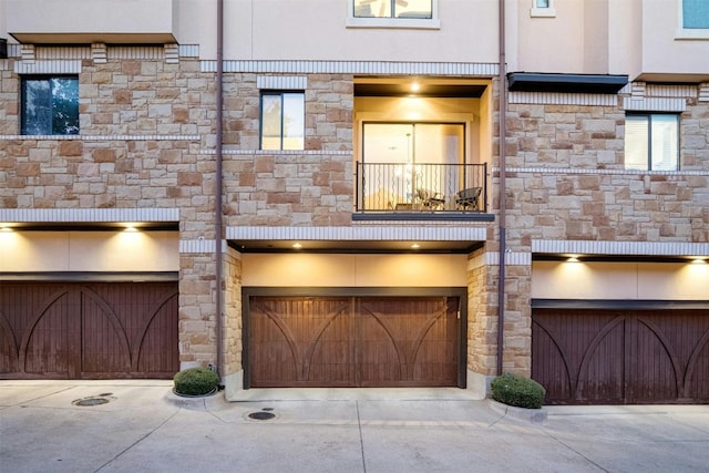 multi unit property with stone siding, an attached garage, and stucco siding