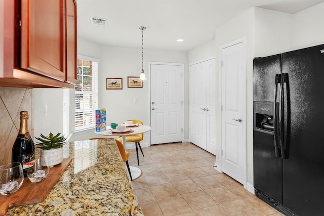 508 Sheldon Lake Dr, Georgetown, TX 78633 - kitchen featuring black refrigerator with ice dispenser, light tile patterned floors, light stone countertops, pendant lighting, and recessed lighting