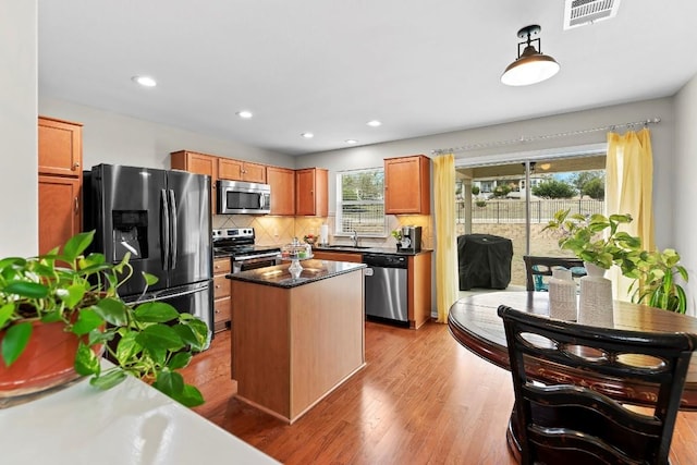 kitchen featuring visible vents, hanging light fixtures, backsplash, appliances with stainless steel finishes, and light wood-type flooring