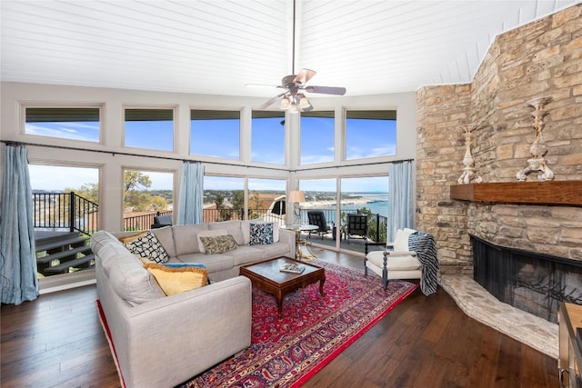 living room featuring ceiling fan, a stone fireplace, a wealth of natural light, and hardwood / wood-style flooring
