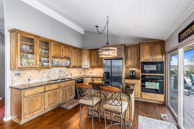 kitchen featuring black appliances, vaulted ceiling, brown cabinets, and a sink
