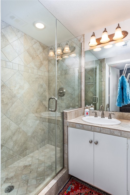 full bathroom with a stall shower, visible vents, and vanity