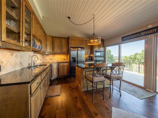 kitchen with oven, built in microwave, a sink, stainless steel fridge with ice dispenser, and brown cabinets