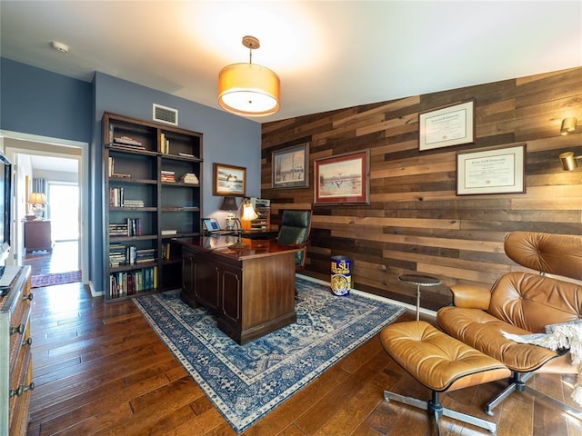 home office featuring dark wood-style floors, visible vents, and wood walls