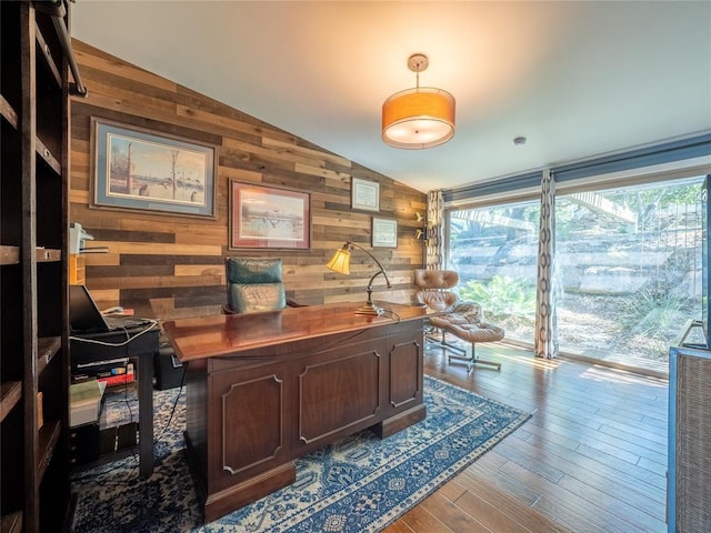 home office with vaulted ceiling, wood walls, and wood finished floors