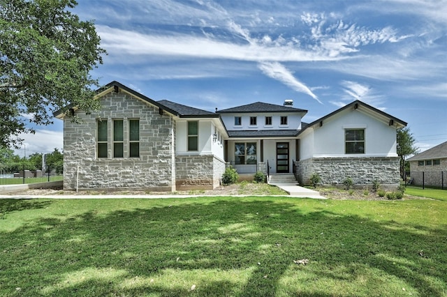 view of front facade with covered porch, stone siding, a front yard, and fence