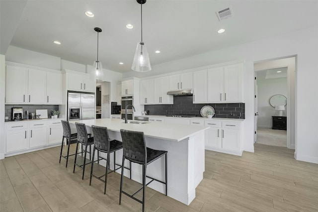 1635 Nature View Loop, Driftwood, TX 78619 - kitchen featuring stainless steel fridge, a sink, under cabinet range hood, black electric stovetop, and a large island with sink