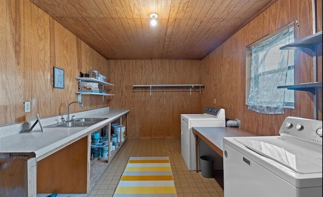 clothes washing area featuring laundry area, wooden ceiling, washer and dryer, light floors, and a sink