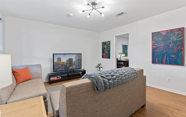 living room with a chandelier, visible vents, baseboards, and wood finished floors