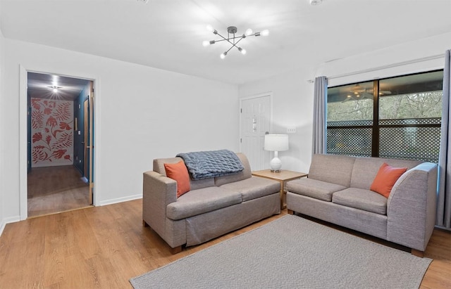 living area featuring light wood-type flooring, baseboards, and an inviting chandelier