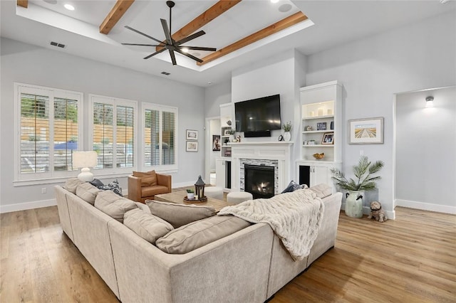 living area with light wood-style flooring, a fireplace, visible vents, and baseboards