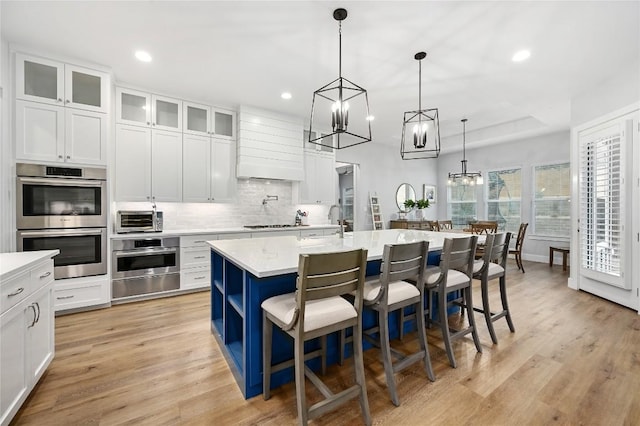 233 Lakefront Dr, Lago Vista, TX 78645 - kitchen featuring a kitchen island with sink, backsplash, double oven, a notable chandelier, and a warming drawer