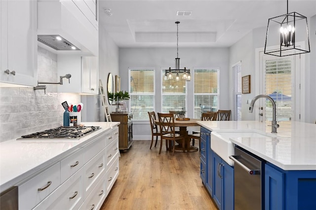 kitchen with decorative light fixtures, a tray ceiling, white cabinets, and blue cabinets