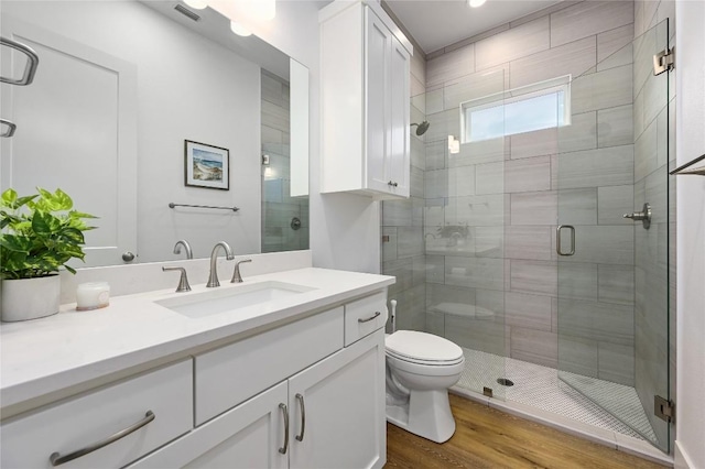 full bathroom featuring toilet, wood finished floors, visible vents, vanity, and a stall shower