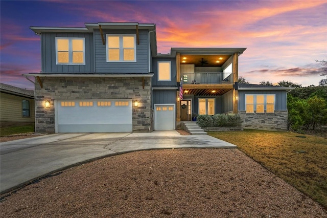 modern home with a balcony, a garage, stone siding, driveway, and board and batten siding