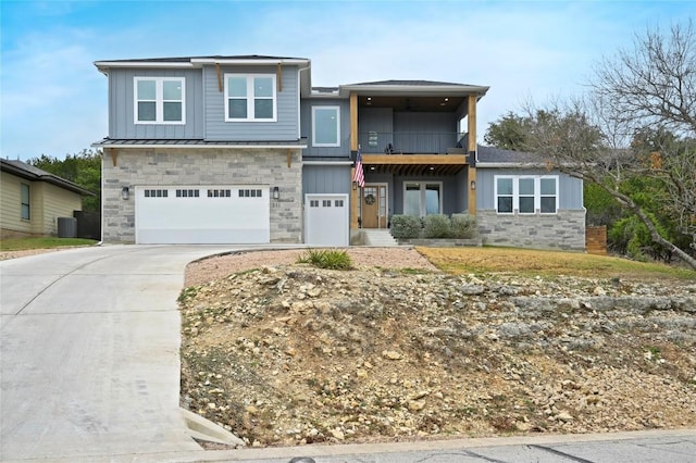 view of front of house with concrete driveway, an attached garage, board and batten siding, central AC, and stone siding