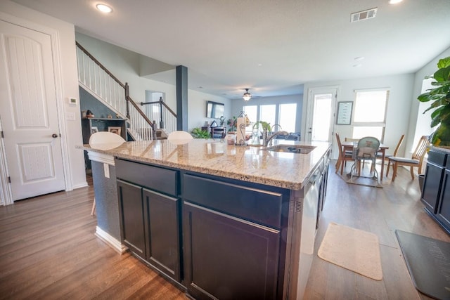 5864 Bianca Dr, Round Rock, TX 78665 - kitchen featuring a sink, ceiling fan, dark wood-style floors, light stone counters, and an island with sink