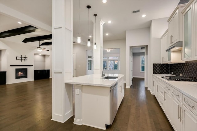 kitchen featuring visible vents, a ceiling fan, a sink, under cabinet range hood, and gas cooktop