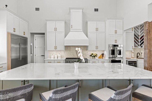 kitchen with a breakfast bar area, visible vents, white cabinets, a large island, and appliances with stainless steel finishes