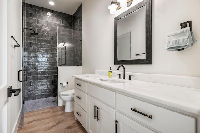 bathroom featuring toilet, a stall shower, vanity, and wood tiled floor