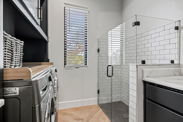 full bathroom featuring baseboards, wood finished floors, independent washer and dryer, vanity, and a shower stall