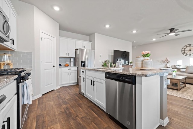 kitchen with white cabinets, appliances with stainless steel finishes, dark wood-type flooring, a center island, and a sink