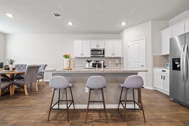 kitchen with an island with sink, white cabinetry, visible vents, and stainless steel appliances