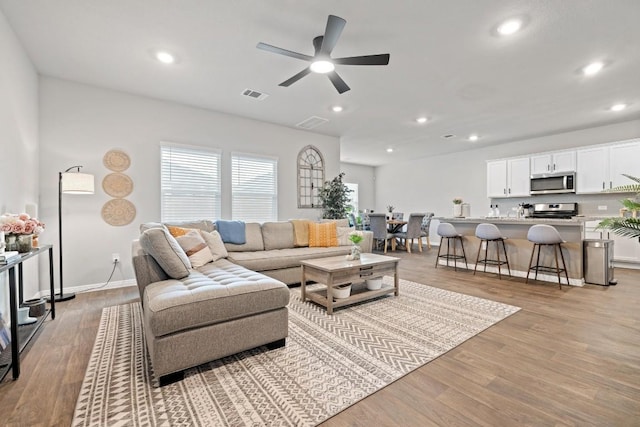 living area with light wood-style floors, ceiling fan, visible vents, and recessed lighting