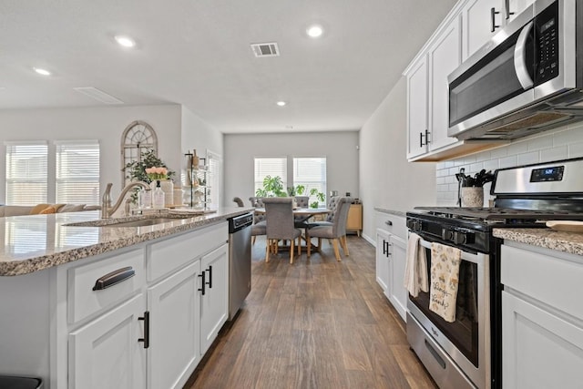 kitchen featuring stainless steel appliances, tasteful backsplash, visible vents, dark wood-type flooring, and white cabinets