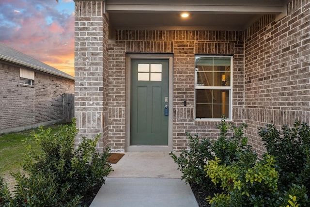 view of exterior entry featuring brick siding
