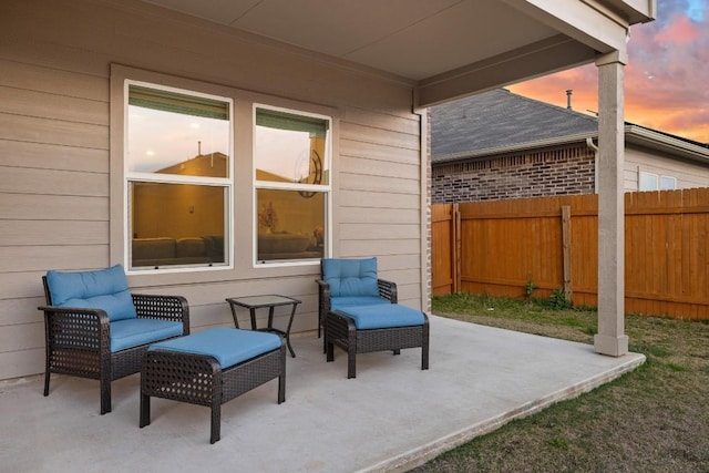 patio terrace at dusk featuring fence and an outdoor hangout area