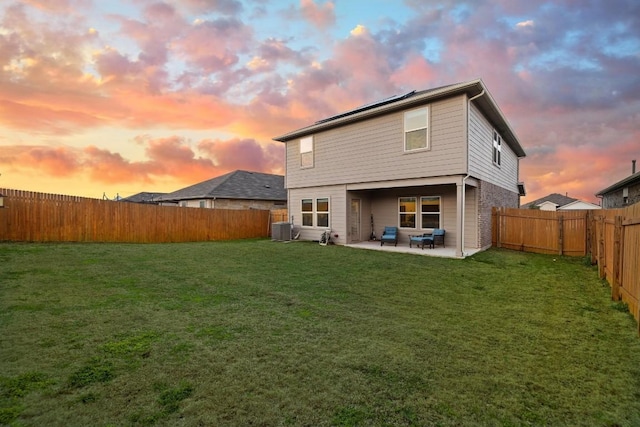 rear view of property with central AC, a patio, a fenced backyard, and a lawn