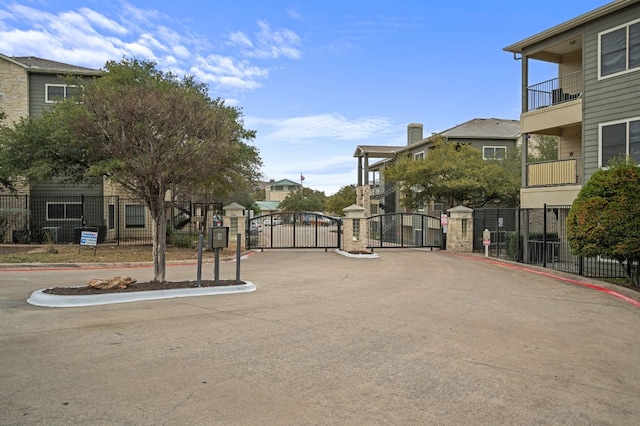 view of road featuring a residential view, a gate, a gated entry, and curbs