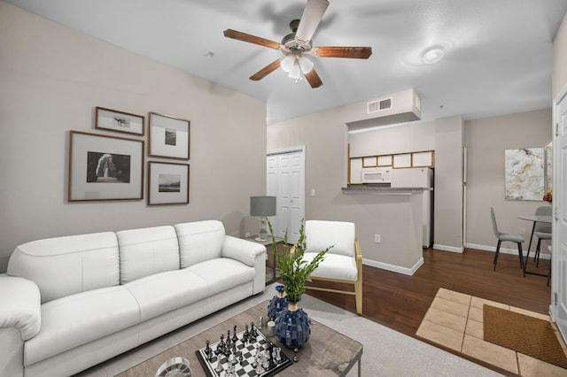 living room with dark wood-type flooring, a ceiling fan, visible vents, and baseboards