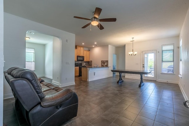 interior space featuring visible vents, baseboards, arched walkways, a sink, and ceiling fan with notable chandelier