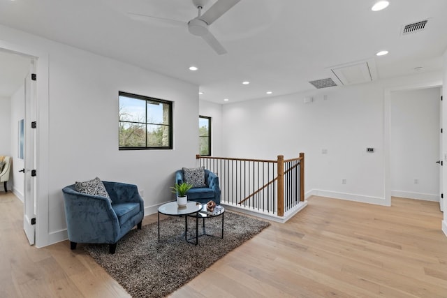 sitting room with light wood finished floors, attic access, visible vents, and an upstairs landing