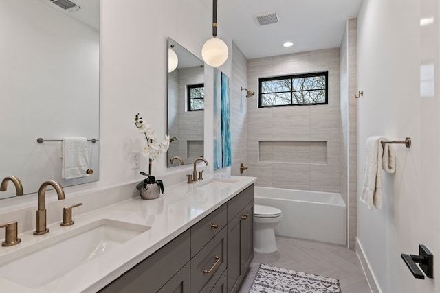 bathroom with toilet, double vanity, visible vents, and a sink