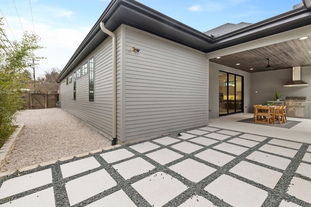 view of patio / terrace featuring an outdoor kitchen, a ceiling fan, grilling area, fence, and outdoor dining space