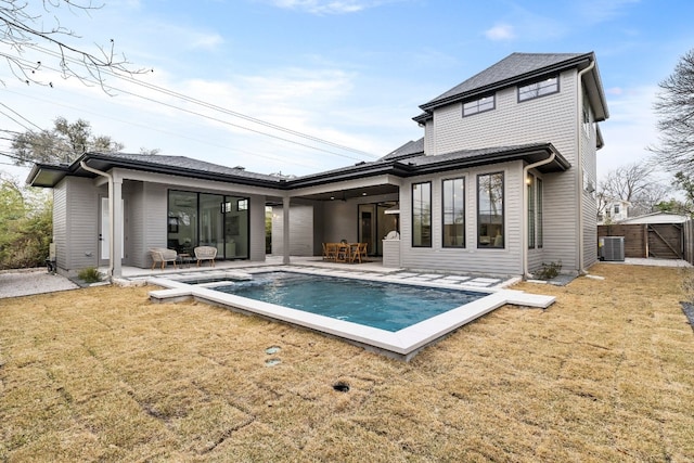 rear view of property featuring a patio area, an outdoor pool, central AC, and a yard