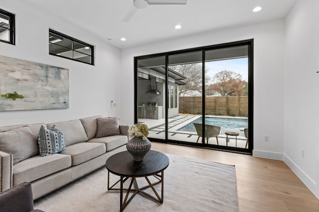 living area with baseboards, light wood finished floors, a ceiling fan, and recessed lighting