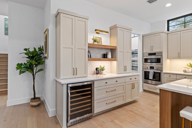 kitchen featuring beverage cooler, light countertops, double oven, open shelves, and backsplash